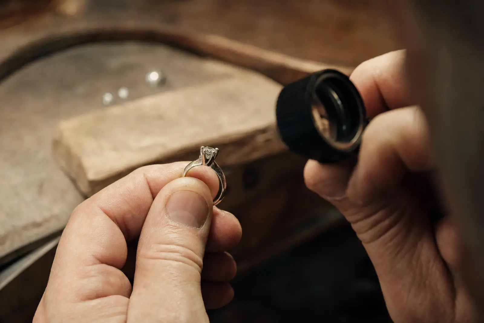 A ring held under a jeweller's loupe with a claw and stone visible at close range