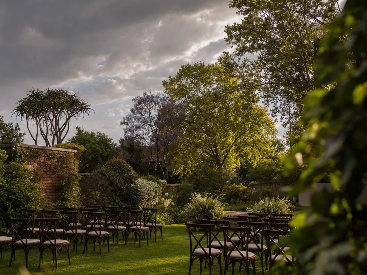 A walled Johannesburg garden set for an evening wedding, storm clouds clearing to the west