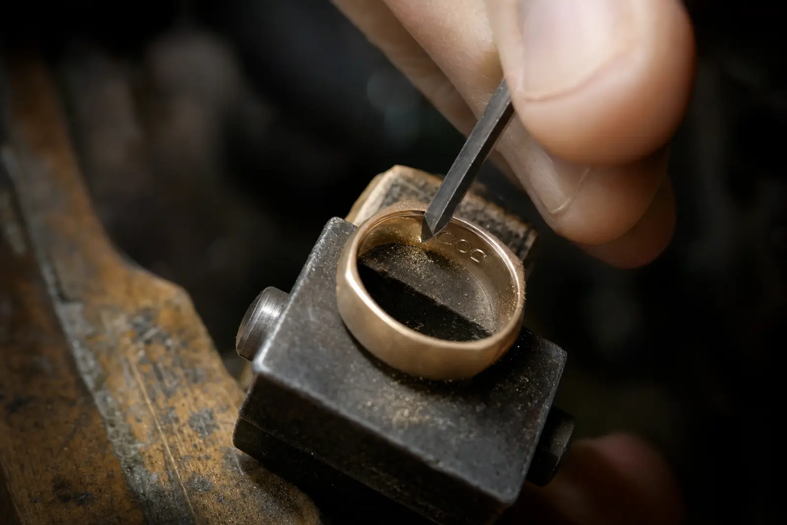 A graver cutting a line of engraving inside a wedding band