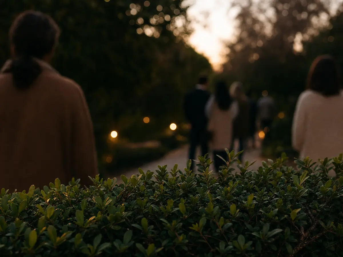 A small group of blurred figures waiting at a distance behind a garden hedge