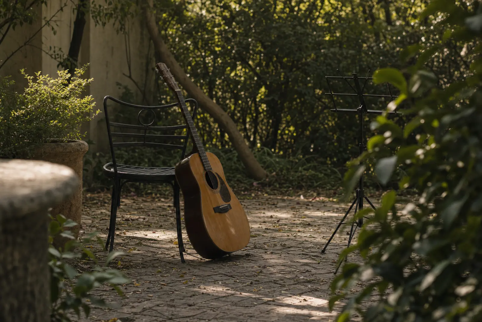An acoustic guitar leaning against a garden chair beside a folded music stand