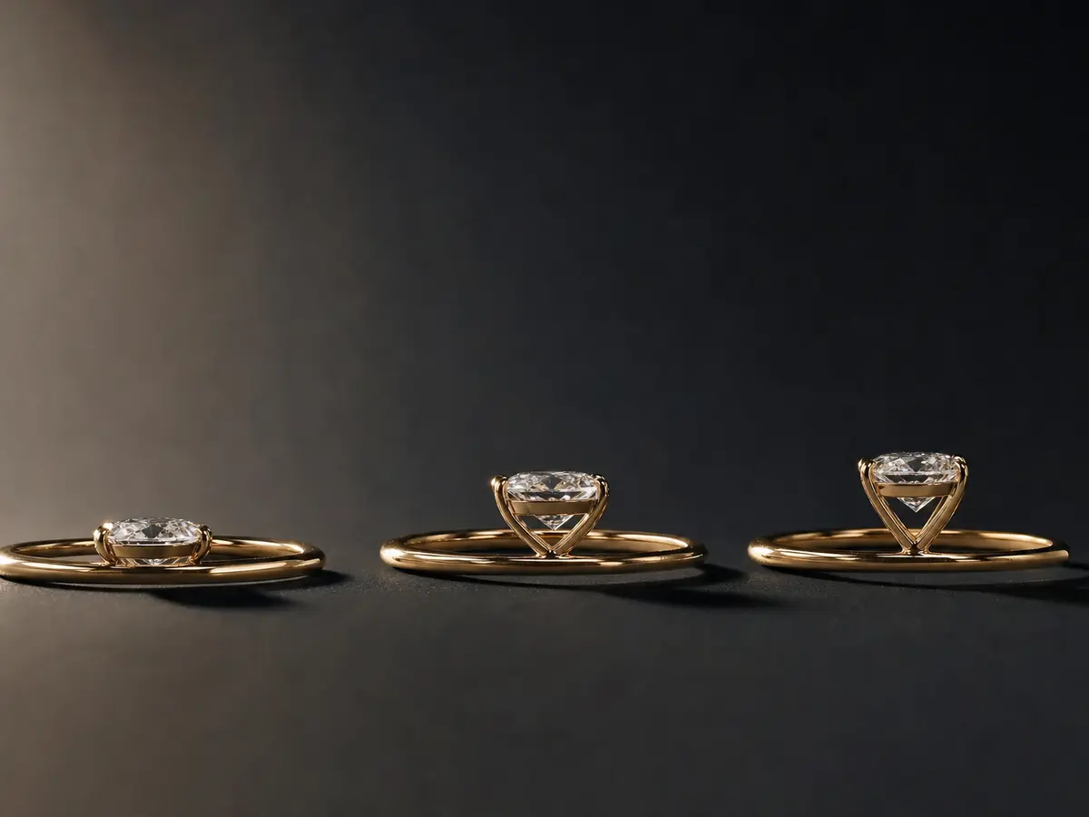 Three engagement rings of low, mid and high profile height lined up side-on on a dark ground