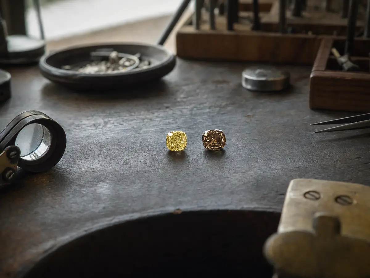 A loose fancy yellow diamond beside a loose champagne diamond on a bench