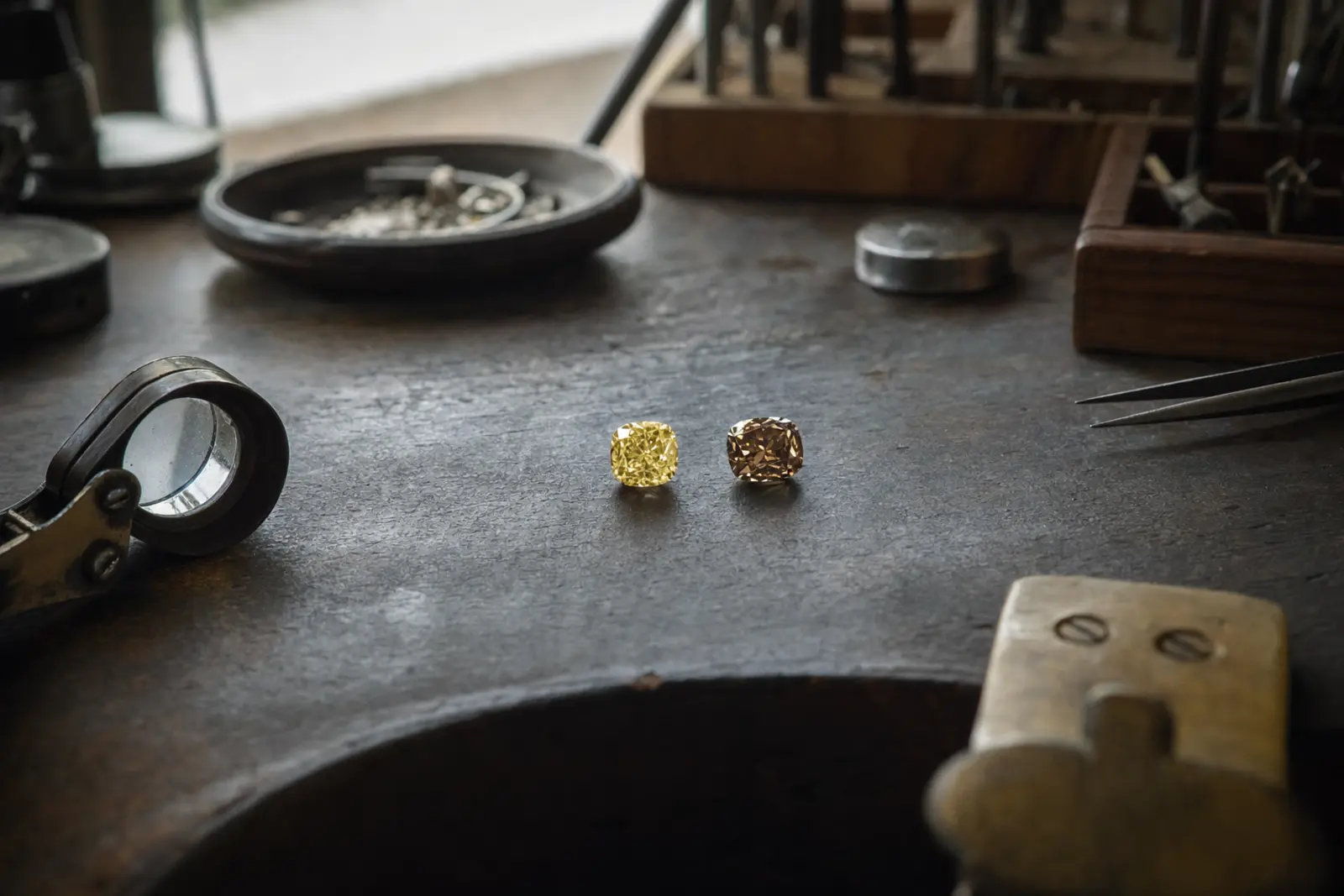 A loose fancy yellow diamond beside a loose champagne diamond on a bench